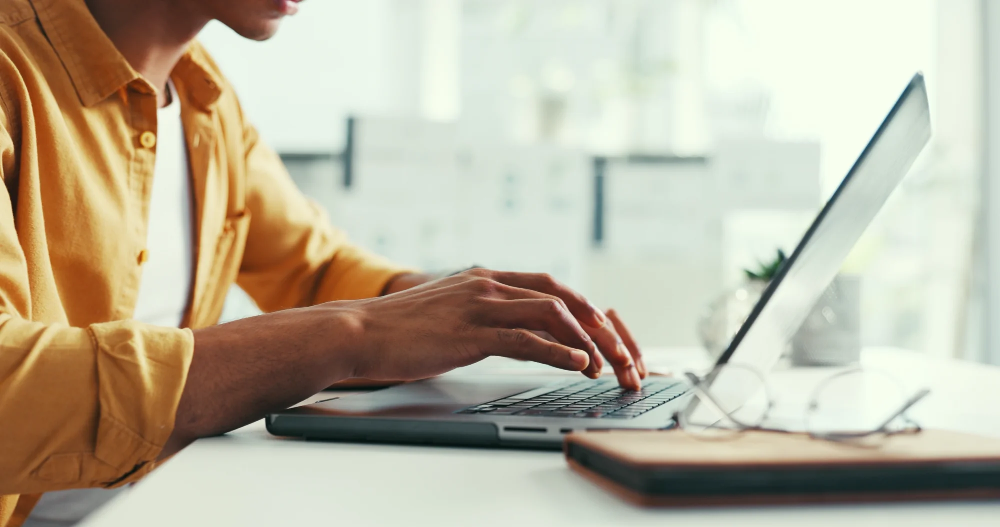 Person typing with their arms rested on the table